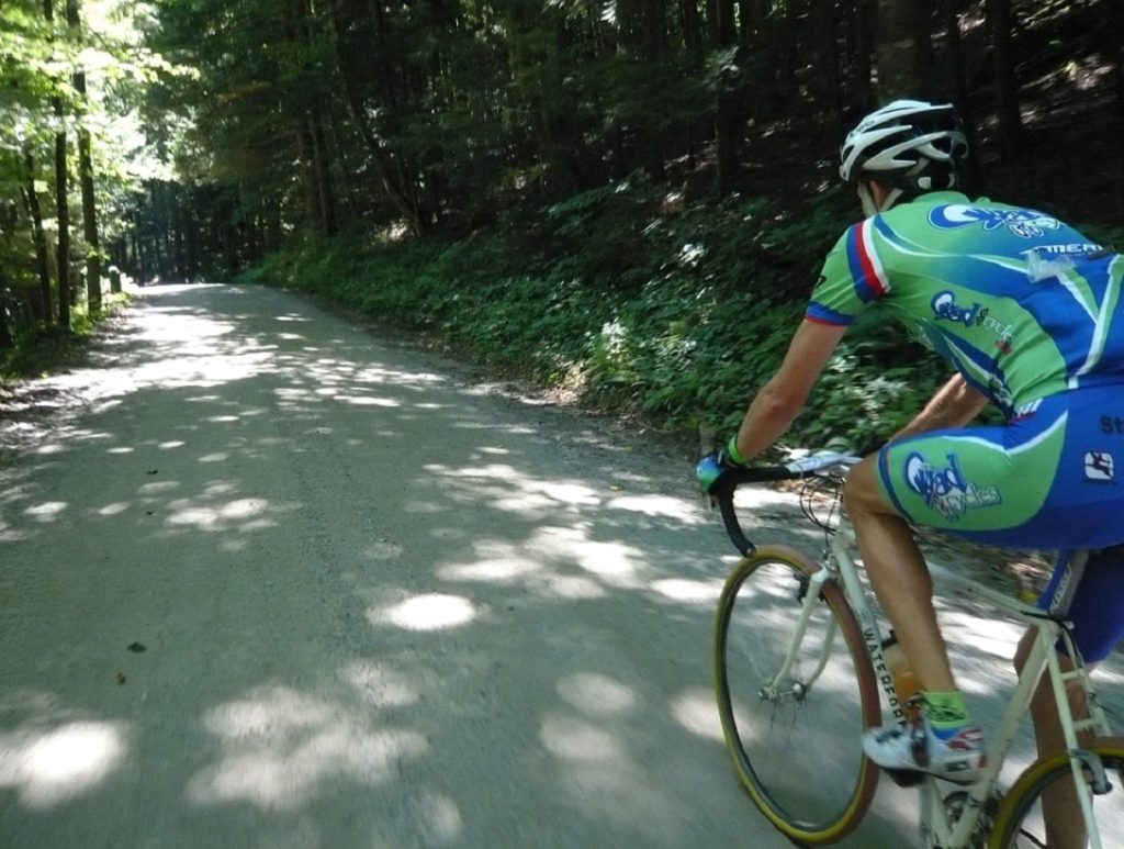 Gerry Waterford biking on a dirt road shaded by trees.